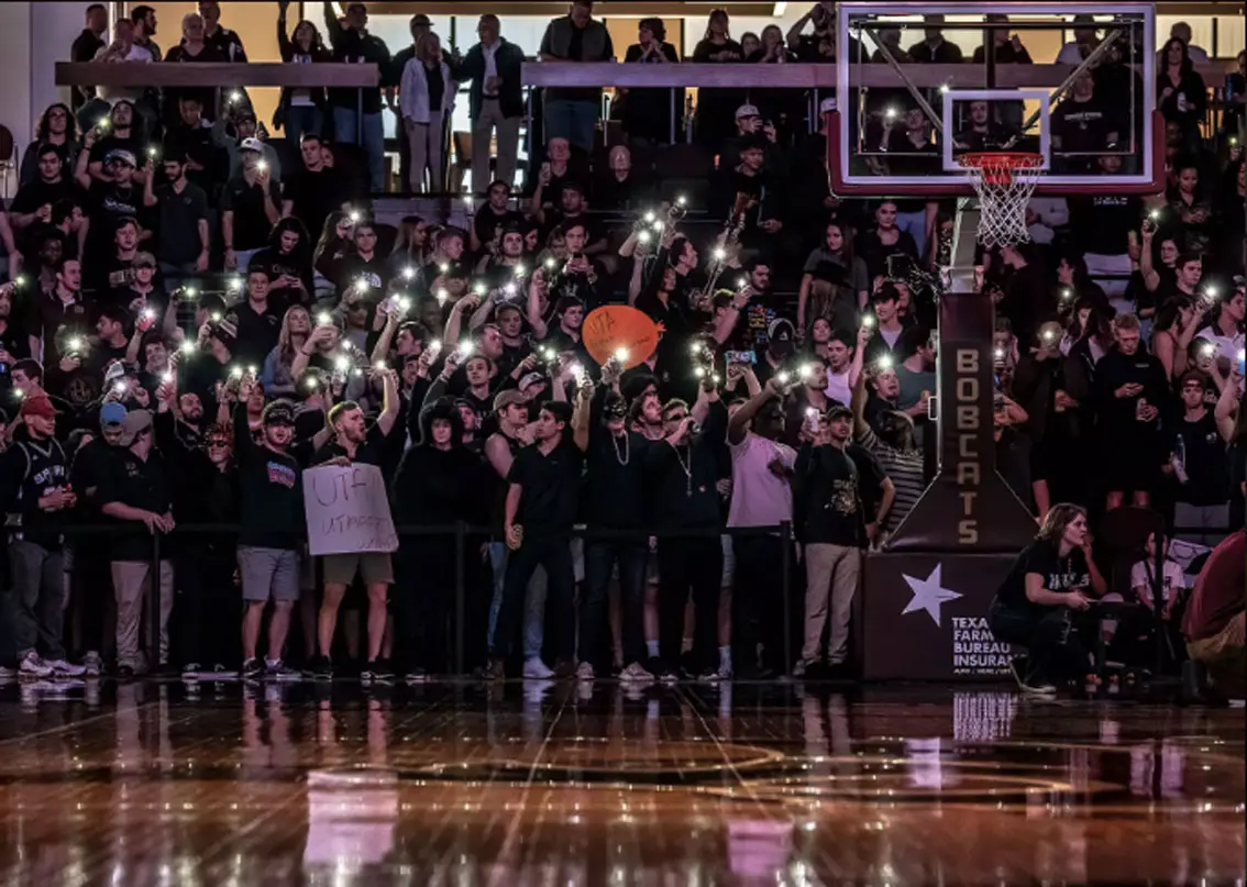 Fans holding up flashlights in basketball arena